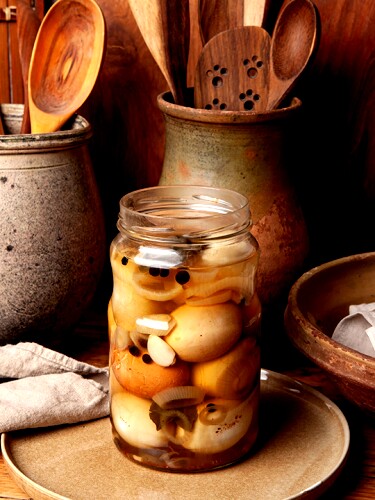 Hard-boiled chicken eggs are pickled in vinegar with spices (pepper, chili peppers, garlic, onion, and salt). The eggshells are crushed, and the jar is refrigerated for about a week.