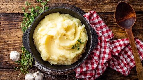 Mashed potatoes, boiled puree in a cast iron pot on a dark wooden rustic background, top view.