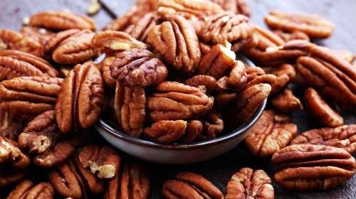 Pecan nuts on a rustic wooden table and pecan nuts in bowl.